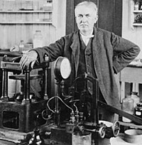 Thomas Edison standing near electrical equipment in his laboratory